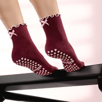 Elliosa Bordeaux Bow grip socks worn on a Pilates reformer