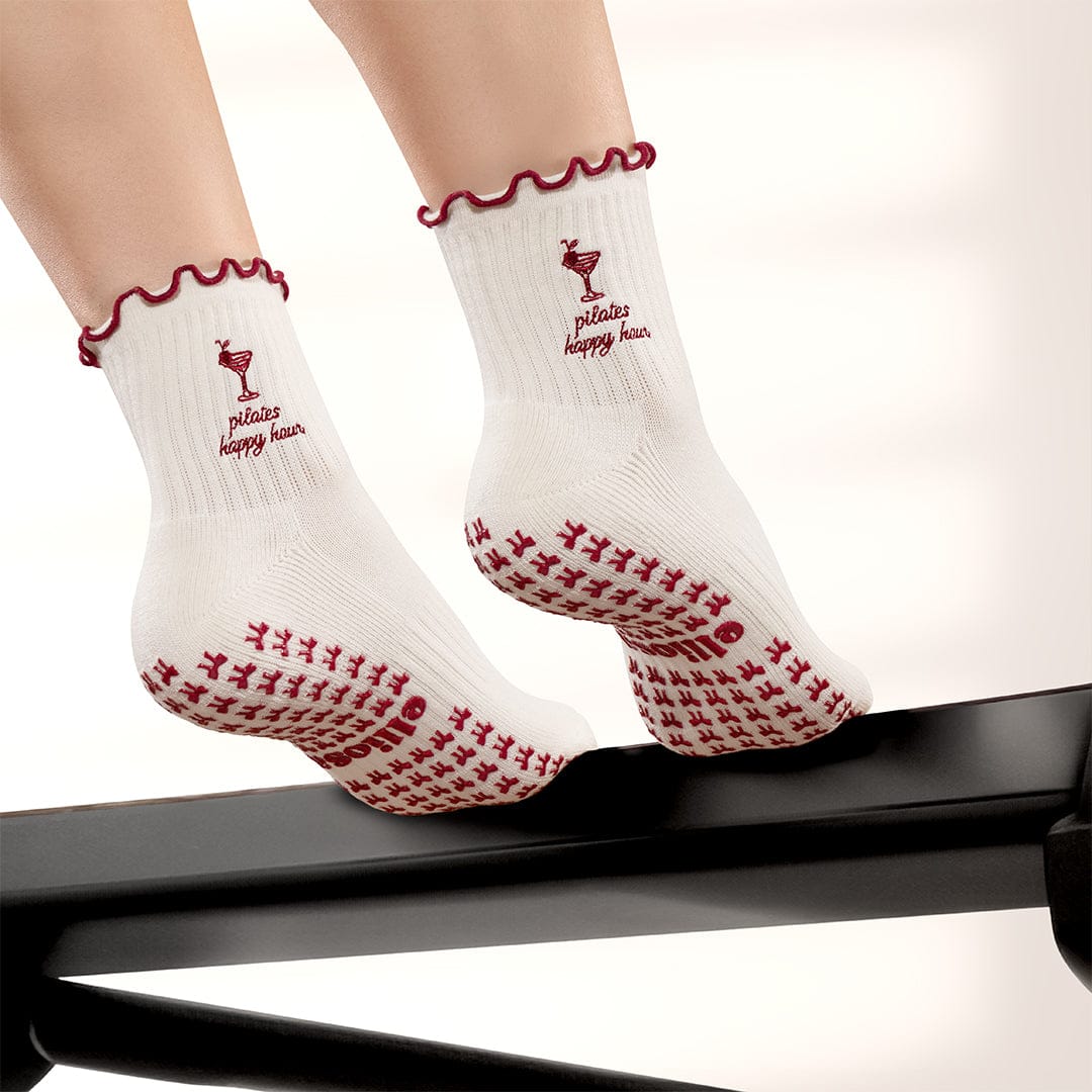 Pilates Happy Hour ruffle grip socks worn on a Pilates reformer