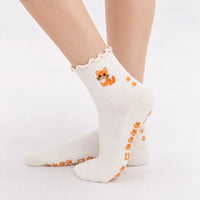 Orange Cat Grip Sock worn with paw-print grip soles visible